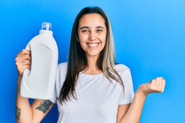 Deterjan şişesini tutan genç İspanyol kadın gururla bağırıyor, zaferi kutluyor ve başarıyı kollarını kaldırarak kutluyor. 