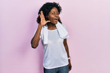 Genç Afro-Amerikalı kadın spor kıyafetleri ve havlu giymiş. Kulaktan kulağa gülümsüyor. Dedikoduları ve dedikoduları dinliyor. Sağırlık kavramı. 