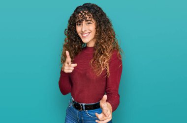 Günlük kıyafetler giyen genç İspanyol kız mutlu ve komik yüzüyle kamerayı işaret ediyor. iyi enerji ve titreşimler. 