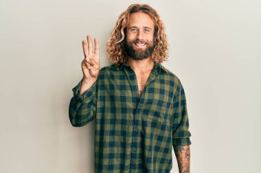 Sakallı, uzun saçlı, sıradan kıyafetler giyen, üç numaralı parmaklarıyla işaret eden, kendinden emin ve mutlu bir adam.. 