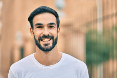 Genç İspanyol adam gülümseyerek şehirde mutlu mesut dikiliyor..