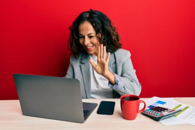 Ofiste çalışan orta yaşlı güzel bir kadın bir fincan kahve içerek mutlu, güler yüzlü, dostça bir jest yapıyor. 