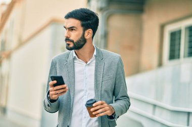 Zeki telefon kullanan ve şehirde kahve içen Latin asıllı genç bir işadamı..