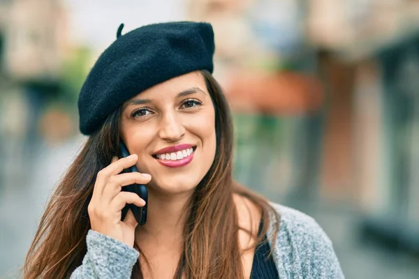 Young latin woman wearing french style talking on the smartphone at the city.