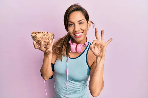 Young Latin Woman Wearing Gym Clothes Using Headphones Holding Cornflakes — Stock Photo, Image