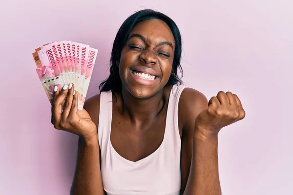 Joven Mujer Afroamericana Sosteniendo Billetes Rupias Indonesias Gritando Orgullosa Celebrando — Foto de Stock