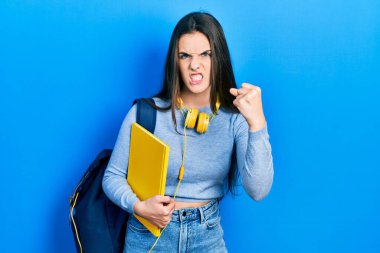 Öğrenci çantası ve kulaklığı takan genç esmer kız öfkeyle bağırıyor, öfkeyle bağırıyor ve el kaldırıyor. 