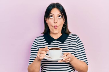 Genç İspanyol kadın bir fincan kahve içiyor. Ağızlı balık suratı yapıyor ve şaşı bakıyor. Deli ve komik.. 