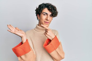 Sıradan bir kazak giyen İspanyol genç adam kameraya hayret ediyor ve gülümsüyor.. 