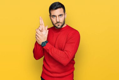 Latin asıllı genç adam gündelik giysiler giyiyor. Elinde sembolik bir silah var. El hareketleriyle cinayet silahlarıyla oynuyor. 