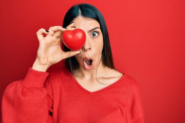 Genç İspanyol kadın kalbi gözünün üstünde tutuyor. Korkmuş ve şaşkın bir şekilde ağzı açık, şaşırmış, inançsız bir yüz. 