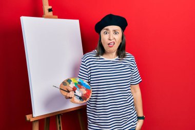 Orta yaşlı, İspanyol bir kadın. Palet üstüne palet çiziyor. Şok olmuş bir yüz ifadesiyle, şüpheci ve alaycı bakıyor. 