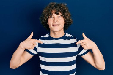 Yakışıklı, çizgili tişört giyen, kendine güvenen, gülümseyen, kendini gururlu ve mutlu gösteren bir genç.. 