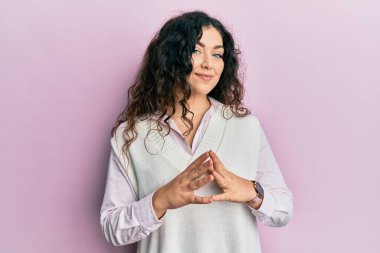 Kıvırcık saçlı, el ele tutuşmuş, gülümseyen, gevşemiş ve neşeli genç esmer kadın. Başarı ve iyimserlik 