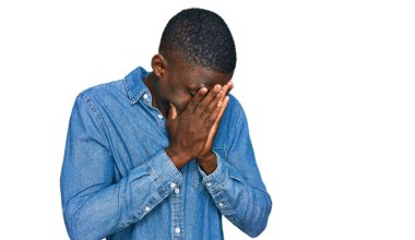 Genç, Afro-Amerikan bir adam, günlük kıyafetler giyiyor ve ağlarken suratını ellerle kapatıyor. depresyon kavramı. 