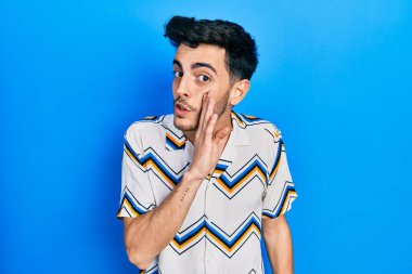 Latin asıllı genç adam, günlük kıyafetlerini giymiş, el ele tutuşmuş, gizli söylentiler yayıyor, kötü niyetli konuşmalar fısıldıyor. 