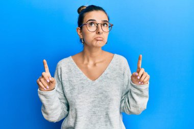 Gündelik kıyafetler giyen genç İspanyol kadın üzgün ve üzgün görünüyor, parmaklarıyla yön gösteriyor, mutsuz ve depresif.. 