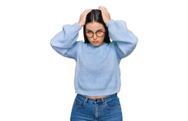 Günlük kıyafetler ve gözlük takan genç İspanyol kadın baş ağrısı ve stres yüzünden acı çekiyor. Çünkü acı ve migren. Eller başının üstünde.. 