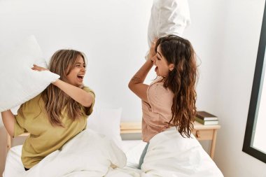 Mutlu gülümseyen genç çift evdeki yatakta yastıklarla kavga ediyor..