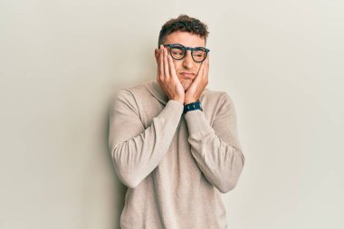 Balıkçı yaka kazak giyen İspanyol genç adam yorgun eller yüzünü kapatıyor, depresyon ve üzüntü, sorun için üzgün ve tedirgin 