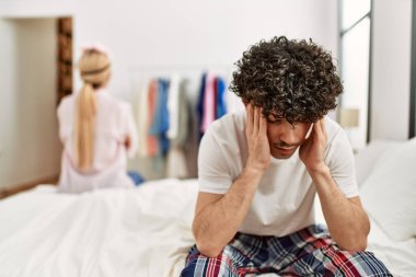 Genç ve güzel bir çiftin başı dertte. Ellerin başının üstünde, yatakta oturuyorsun..