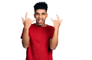 Genç Afro-Amerikan adam, günlük kırmızı tişört giyip çılgın bir ifadeyle bağırıyor elleri havada rock sembolü yapıyor. Müzik yıldızı. ağır kavram. 