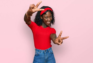 Güzel Afrikalı genç bir kadın, gündelik kıyafetler giyip iki elini de göstererek gülümseyerek zafer işareti yapıyor. İki numara.. 