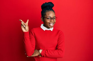 Sıradan kıyafetler ve gözlük takan, kameraya gülümseyen ve zafer işareti yapan Afro-Amerikan genç bir kadın. İki numara.. 