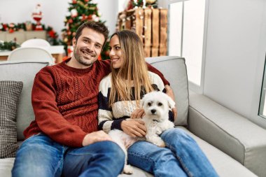 Genç İspanyol çift mutlu bir şekilde kanepede oturuyor ve evde köpekleriyle oturuyor..