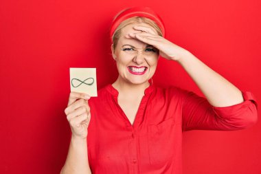 Elinde sonsuz bir sembol tutan genç sarışın kadın elleri kafasında, şaşırmış ve kızgın bir yüzle stresli ve hayal kırıklığına uğramış. 