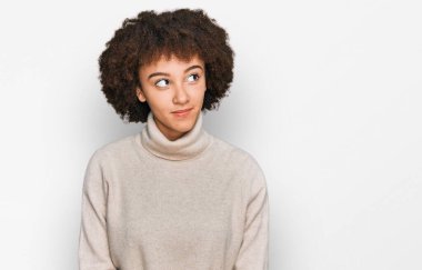 Yün kazak giyen genç İspanyol kız gülümseyip yan tarafa bakıyor ve düşünüyor.. 