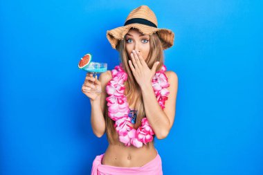 Bikini giyen genç sarışın kız ve Hawaii zambağı içen ağız kaplayan kokteyl içen hata yapmaktan korkan ve şok olan kız. şaşırmış ifade 