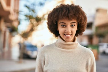 Genç İspanyol kız gülümseyerek şehirde mutlu mesut dikiliyor..