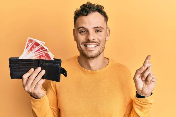 Joven Hispano Sosteniendo Billetera Con Shekels Israelel Sonriendo Feliz Señalando —  Fotos de Stock