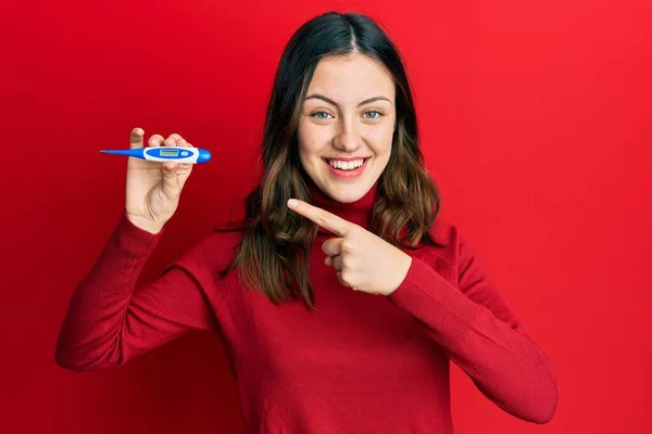 Jovem Morena Segurando Termômetro Sorrindo Feliz Apontando Com Mão Dedo — Fotografia de Stock