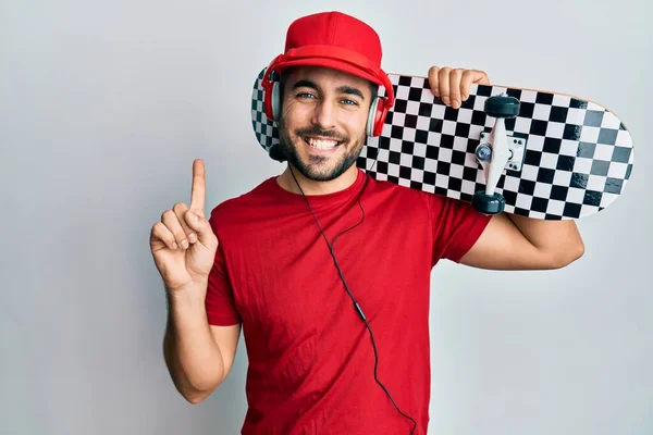 Jovem Hispânico Usando Fones Ouvido Segurando Skate Sorrindo Com Uma — Fotografia de Stock