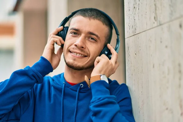 若いですヒスパニック男笑顔幸せな使用ヘッドフォンで市内 — ストック写真