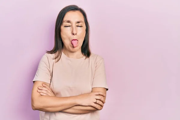 Hispanische Frau Mittleren Alters Mit Verschränkten Armen Die Zunge Herausstreckend — Stockfoto