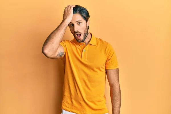 若いヒスパニック系の男性が誤って頭の上に手で驚いて エラーを覚えてカジュアルな黄色のTシャツを着て 忘れられた悪い記憶の概念 — ストック写真