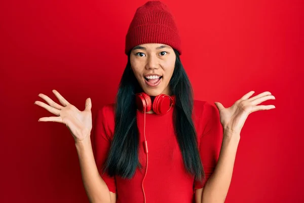 年轻的中国女人一边听音乐 一边用耳机庆祝疯狂的成功 她举起双臂 睁开眼睛尖叫 兴奋极了 获奖者概念 — 图库照片