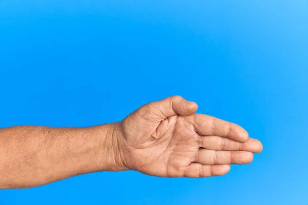 Рука Старшего Латиноамериканца Синем Изолированном Фоне Растягивается Протягивается Открытой Рукой — стоковое фото