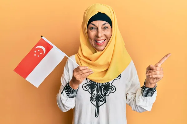 Middle Age Hispanic Woman Wearing Hijab Holding Singapore Flag Smiling — Stock Photo, Image