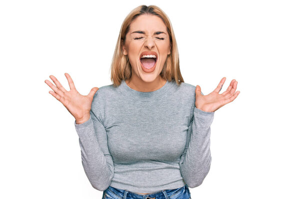 Молодая белая женщина в повседневной одежде празднует безумный и безумный успех с поднятыми руками и с взволнованными закрытыми глазами. победитель концепция 