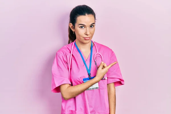 Doktor Üniforması Giyen Genç Esmer Kadın Steteskop Ile Işaret Ediyor — Stok fotoğraf