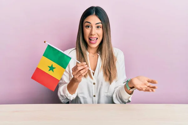 Jovem Hispânica Segurando Bandeira Senegal Sentada Mesa Comemorando Conquista Com — Fotografia de Stock