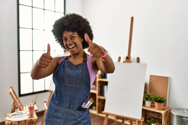 アートスタジオでアフロヘアを持つ若いアフリカ系アメリカ人女性は 手で積極的なジェスチャーを行うことを承認し 親指を上げて笑顔と成功のために幸せ 勝者のジェスチャー — ストック写真