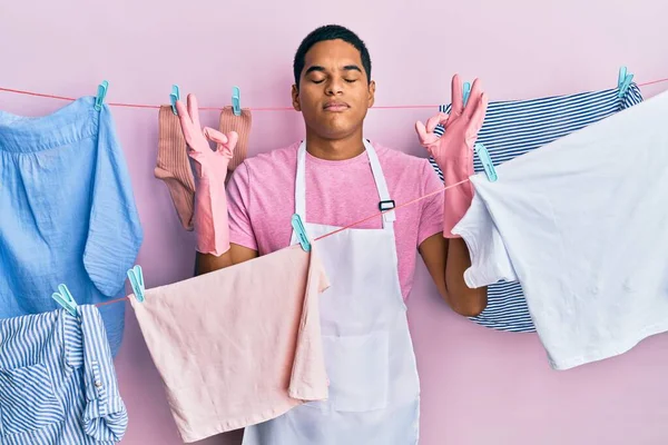 Joven Hombre Hispano Guapo Usando Delantal Más Limpio Sosteniendo Ropa — Foto de Stock