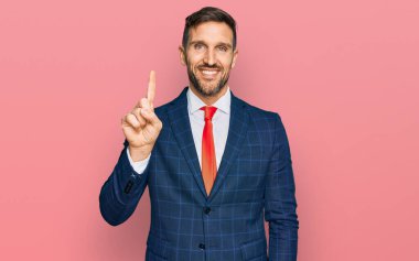 Sakallı, takım elbiseli ve kravatlı yakışıklı bir numaralı parmağını gösterip onu işaret eden kendinden emin ve mutlu bir şekilde gülümseyen adam.. 