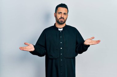 Sakallı, Katolik rahip cübbesi giyen yakışıklı ve kolları açık, hiçbir fikri olmayan bir İspanyol.. 