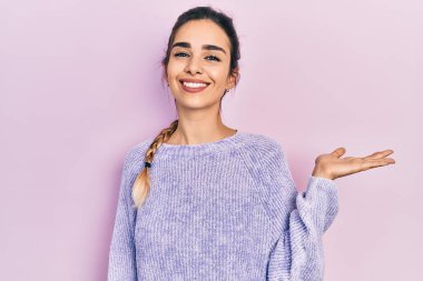 Gündelik kıyafetler giyen, neşeli bir şekilde gülümseyen, avuç içiyle kameraya bakan genç İspanyol kız.. 